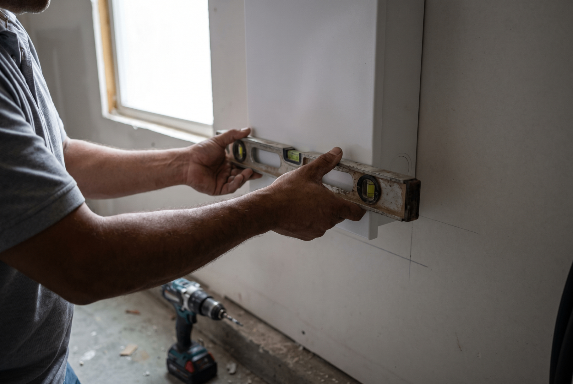 Electrician leveling a wall connector during installation