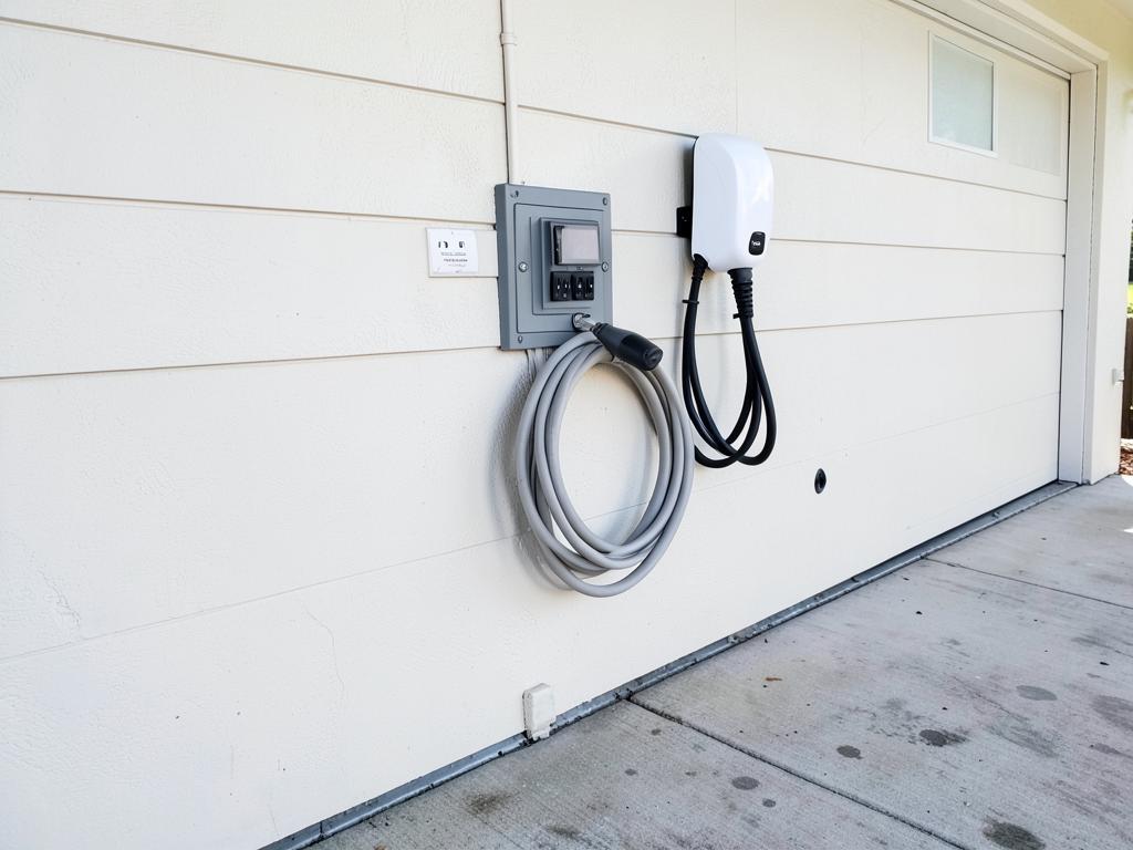 White EV charger installed beside the electrical panel after installation