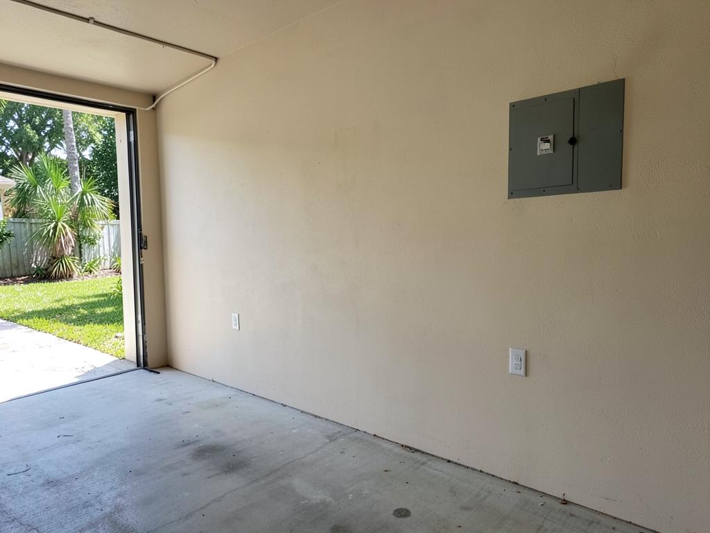 Bare garage wall next to the electrical panel before installation